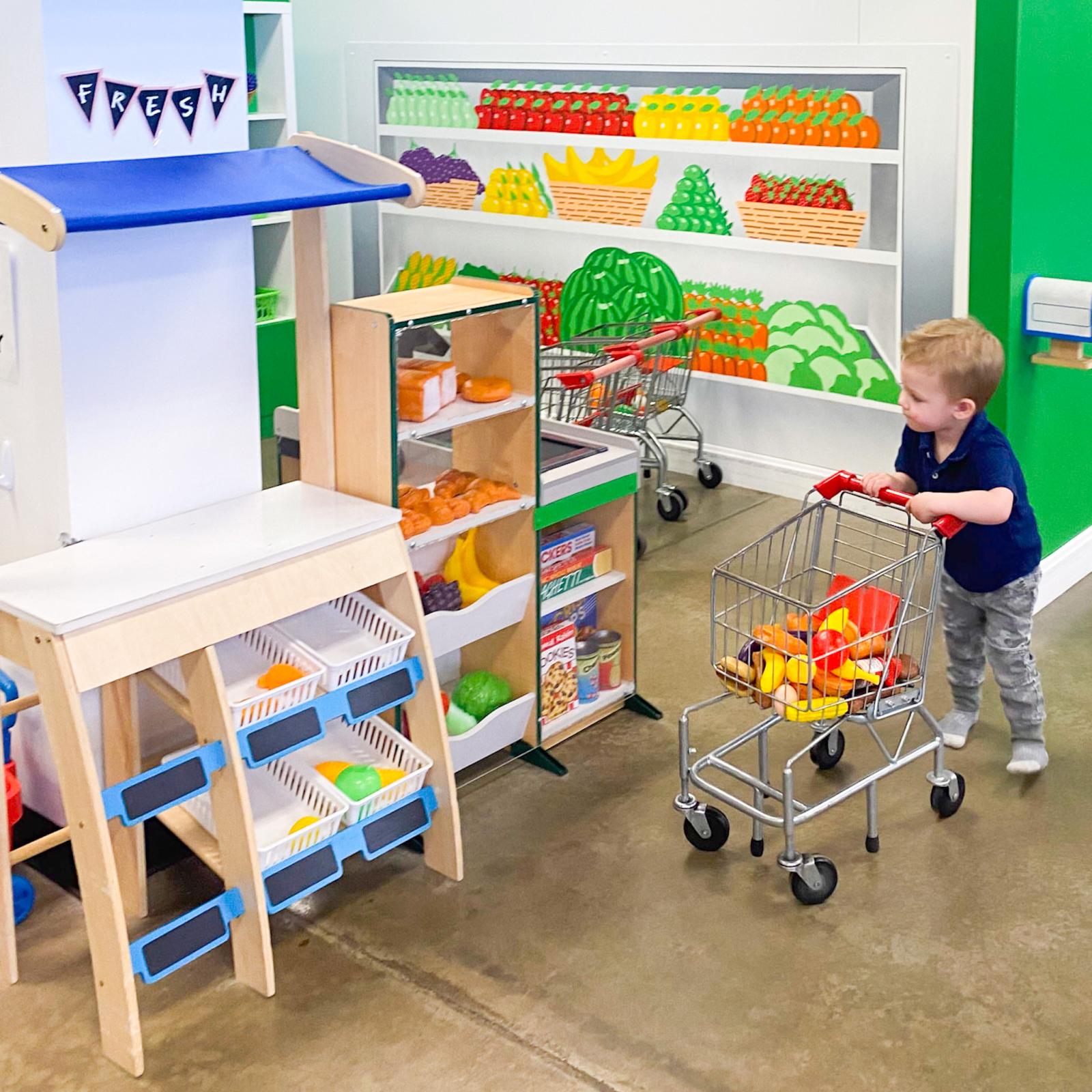 Toddler playing in Kids Wonder grocery store